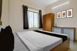 A hotel room with a bed, a desk, and a window with curtains. - Hotel O Golden Aura Near Netaji Subhash (Kolkata)