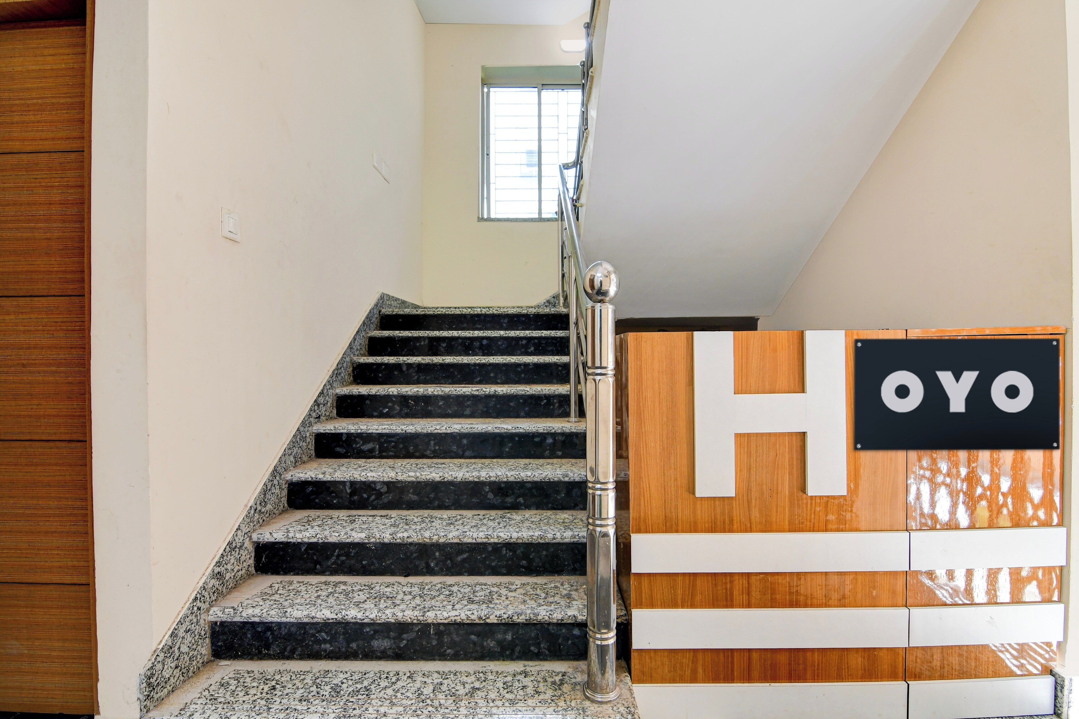 A staircase with a handrail and a sign with the letters 'H' and 'OYO' on the wall.