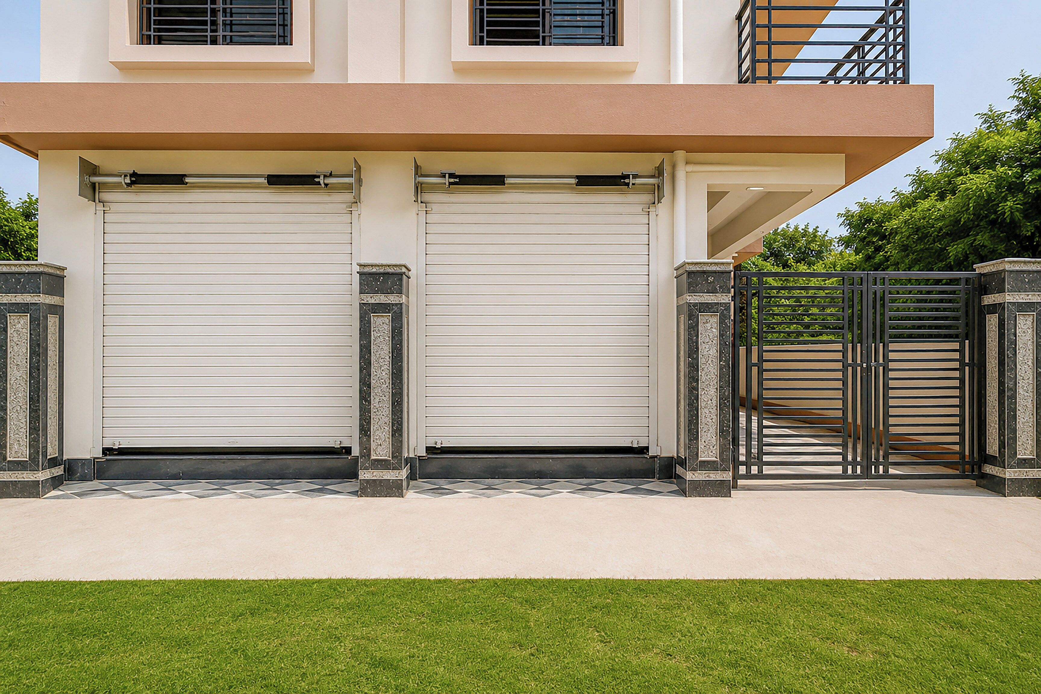 A modern two-story building with a flat roof, two garage doors, and a gated entrance.