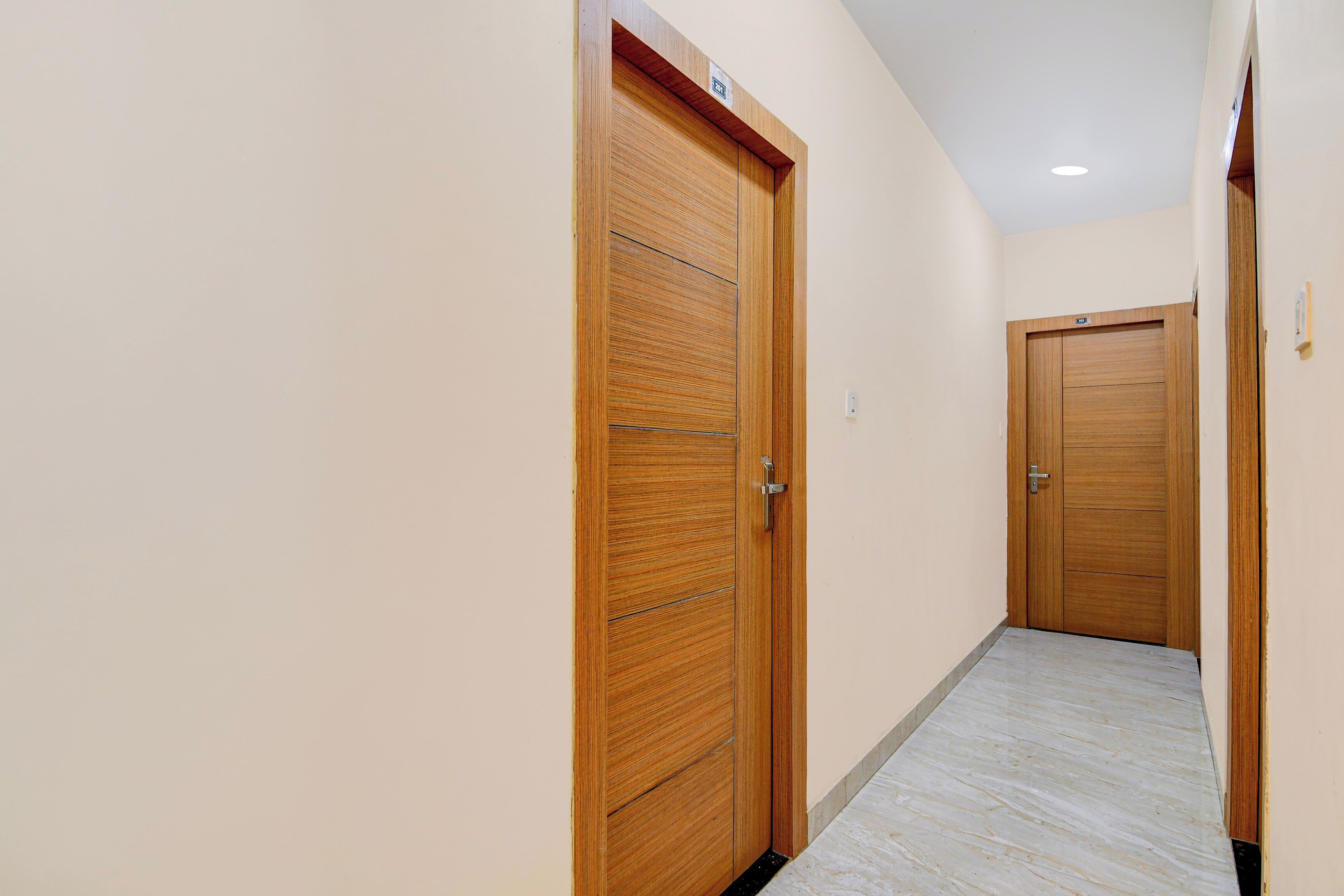 A hallway with wooden doors, a tiled floor, and a ceiling light.