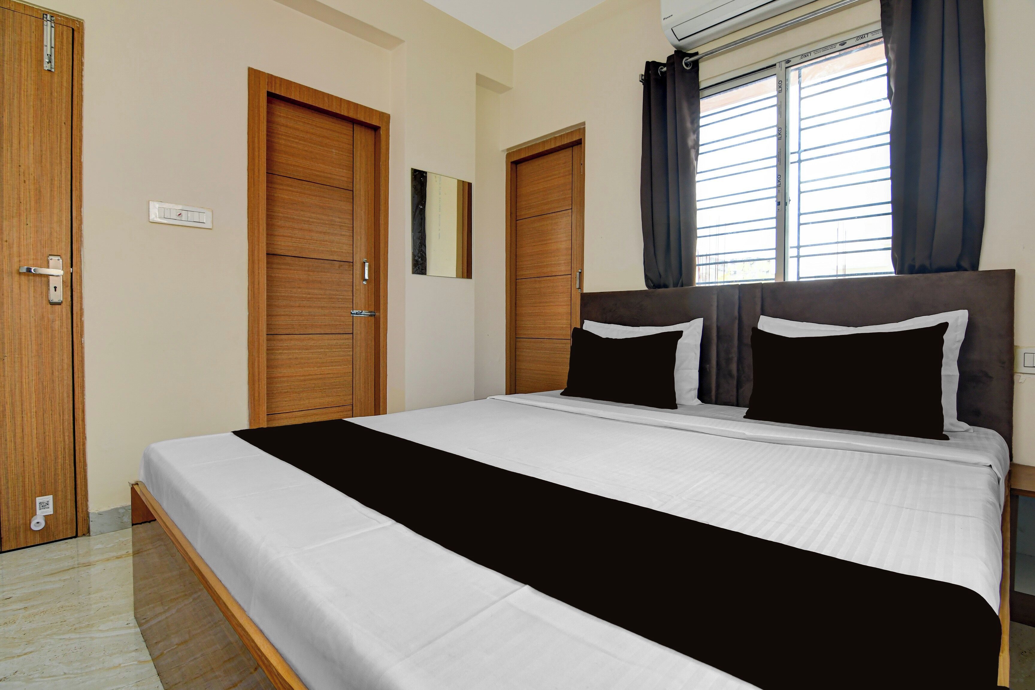 Un dormitorio con cama, armario de madera y ventana con cortinas.