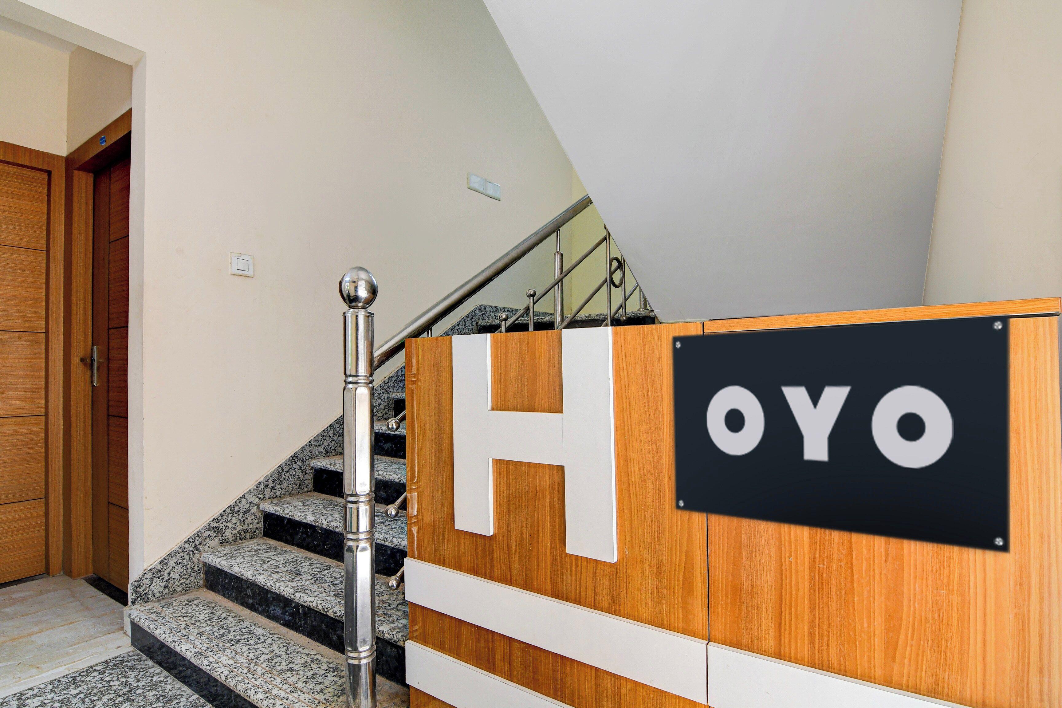 A staircase with a handrail, a wooden door, and a sign with the letters 'H' and 'OYO'.