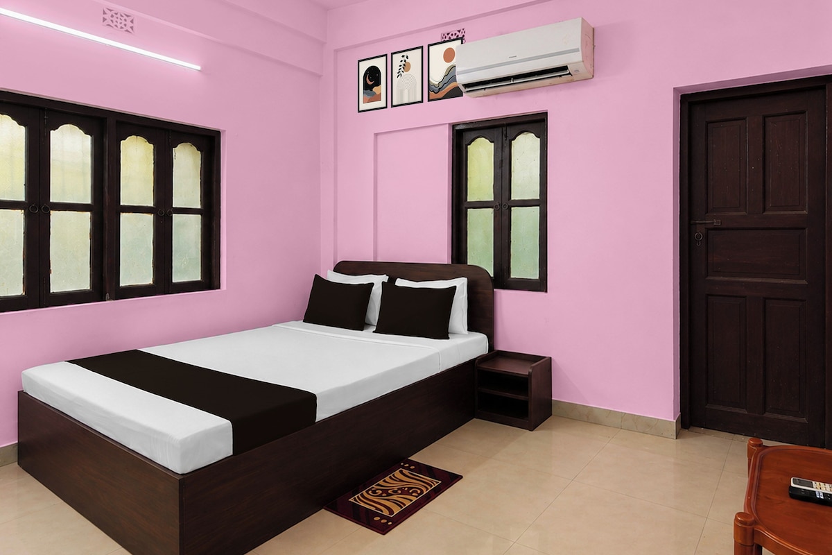 A bedroom with a bed, a nightstand, an air conditioning unit, and a door.