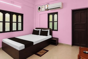 A bedroom with a bed, a nightstand, an air conditioning unit, and a door. - Hotel O Krivaan Guest House (Kolkata)