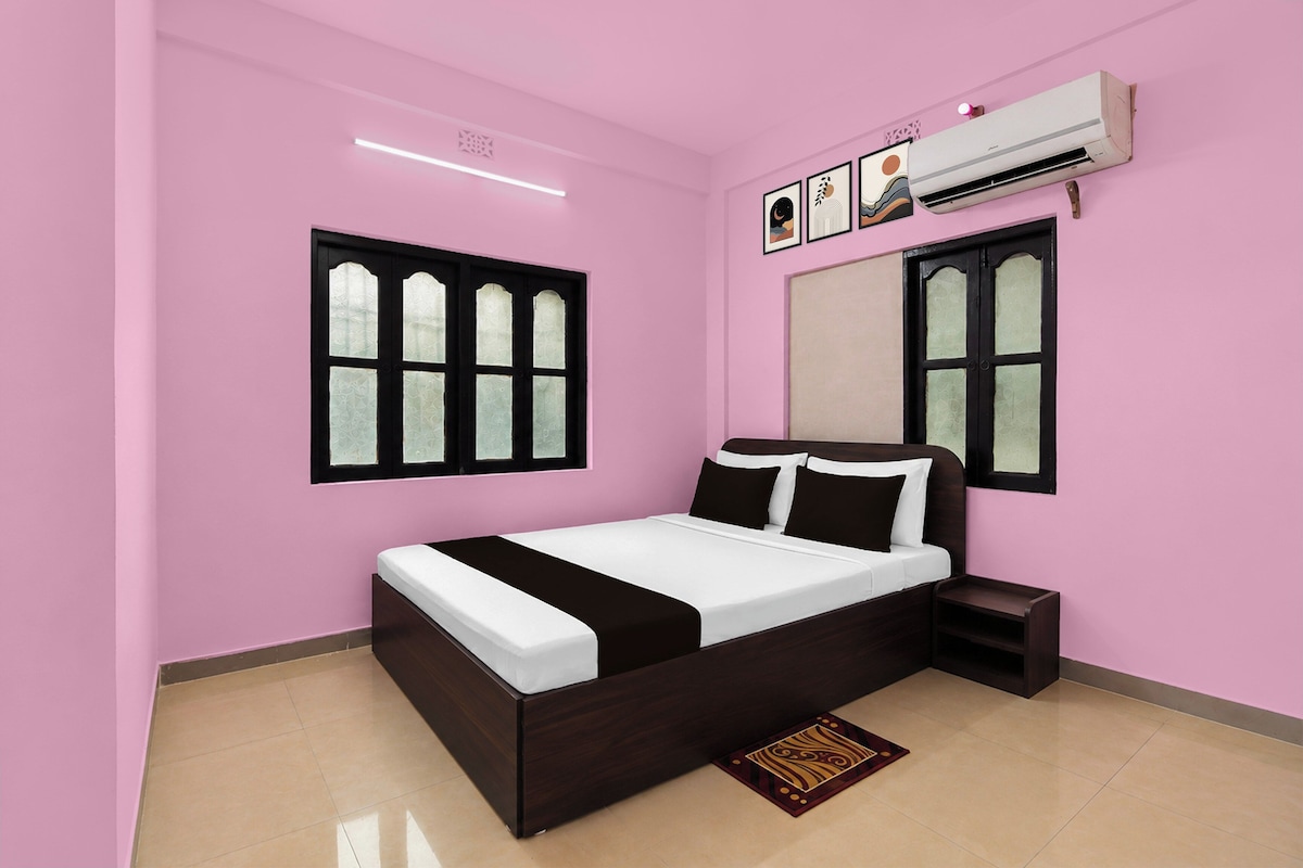 Un dormitorio con cama, mesitas de noche, aire acondicionado y una ventana con detalles decorativos.