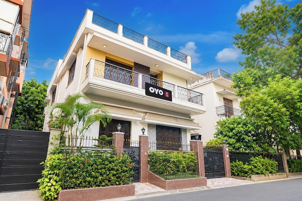 A two-story hotel with a balcony, a gated entrance, and a well-maintained garden. - Hotel O Ghosh Guest House (Barasat)