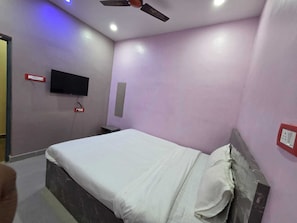 A hotel room with a bed, a ceiling fan, a mounted TV, and a red emergency exit sign. - Hotel O Highway Horizon Inn (Kolkata)