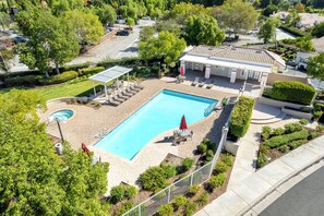 A residential swimming pool with a sun deck, lounge chairs, and a covered patio area. - Elegant Menifee Lakes Retreat with Pool and Spa (Menifee)