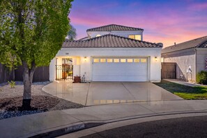 A residential house with a garage, a driveway, and a tree. - Elegant Menifee Lakes Retreat with Pool and Spa (Menifee)