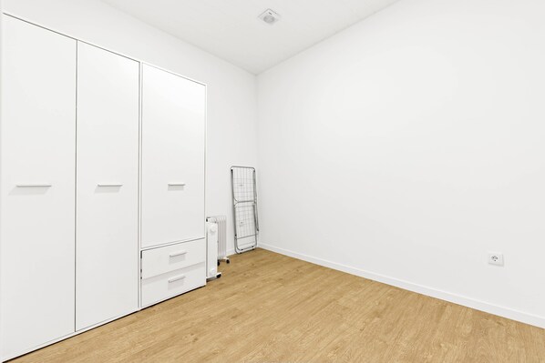 A room with a wooden floor, white walls, a wardrobe, and a radiator. - New Listing (Ponta do Sol)