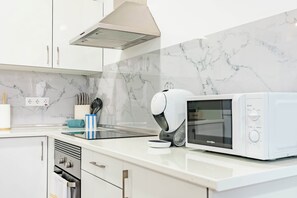 Une cuisine moderne avec des armoires blanches, un four encastré, un four à micro-ondes et une hotte aspirante.