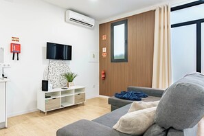 Un salon moderne doté d’un téléviseur à écran plat, d’un meuble de rangement blanc, d’un canapé gris et d’un mur d’accent en bois.