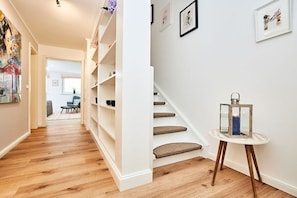 A hallway with a staircase, wooden flooring, and a small table with a lantern. - Holiday apartment with 2 bedrooms (Braderup)