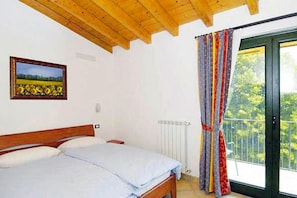 A bedroom with a wooden ceiling, a bed, a window with curtains, and a painting on the wall. - Apartments Cepo, Pieve di Tremosine (Tremosine)