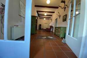 A hallway with a radiator, a chair, and a cabinet with floral decorations. - Rehwinkel Forestry House (Südheide)