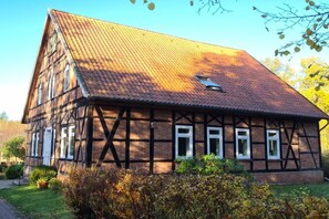 A traditional half-timbered house with a sloped roof, multiple windows, and a small garden area. - Rehwinkel Forestry House (Südheide)