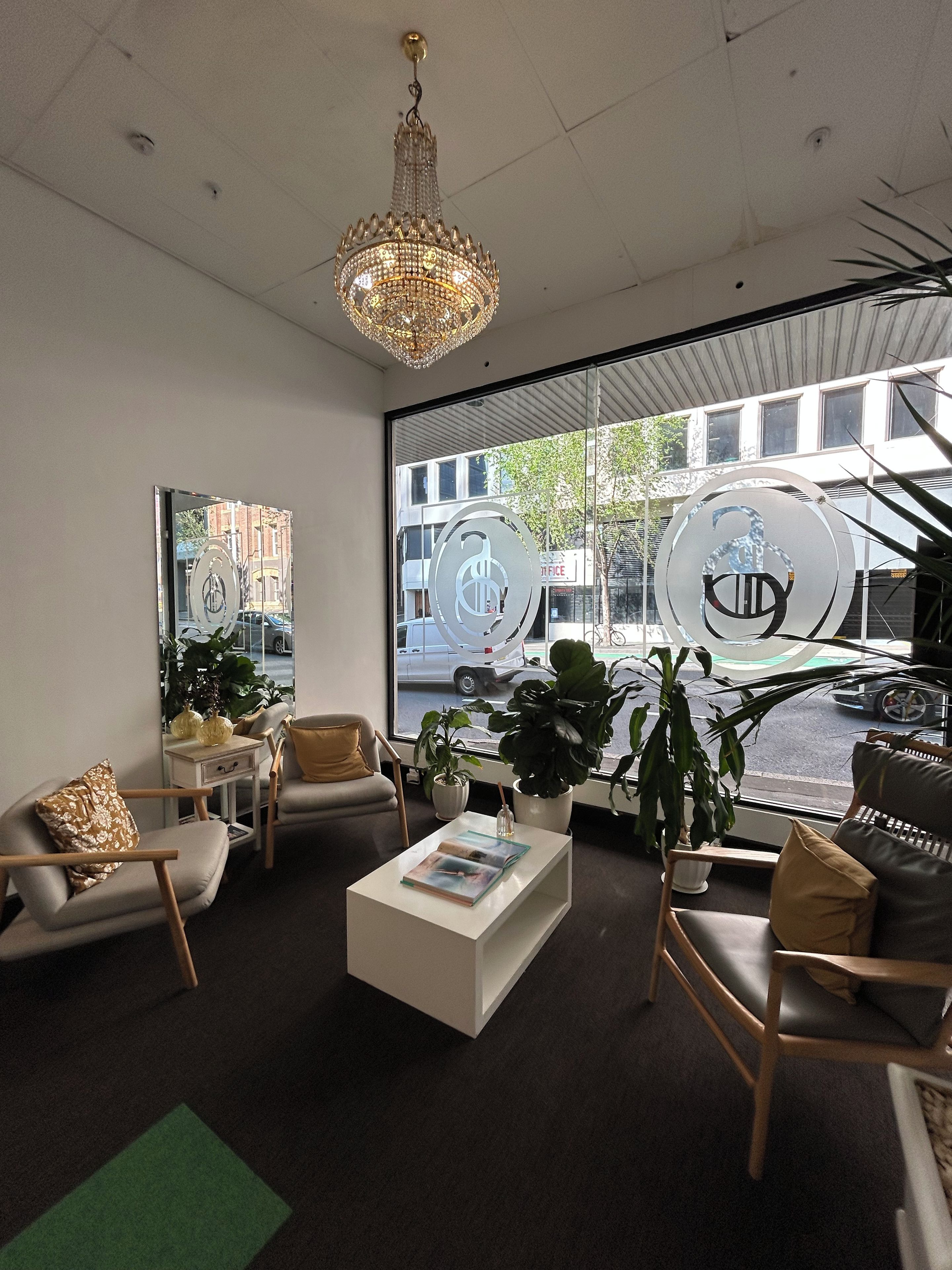 A modern interior with a chandelier, seating area, large windows, and decorative elements.