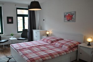 Ein Schlafzimmer mit einem Bett, Nachttischen, einem Schreibtisch und einem Sessel.