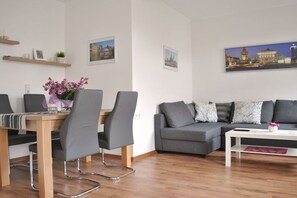 A modern living room with a dining area, grey sofas, a white coffee table, and framed pictures on the walls. - Trade Fair Apartment Lindenau (Leipzig)