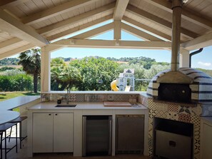Una cocina con horno integrado, un lavamanos y una ventana con vistas a un jardín.