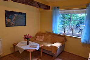 Een gezellige kamer met een houten tafel, een comfortabele zithoek, een kaart aan de muur en een raam met gordijnen.
