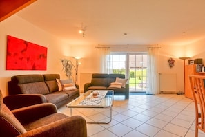 A living room with two sofas, a coffee table, and a large window with curtains. - Schneider Hengsthamm 5b (Hooksiel)
