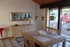 A dining area with a wooden table, chairs, a red bar stool, a cabinet, and a mirror on the wall. - Holiday home with 2 bedrooms (Birkenhördt)
