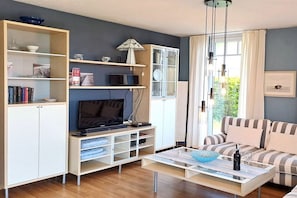 Een moderne woonkamer met een bank, een salontafel, een televisie en ingebouwde kasten.