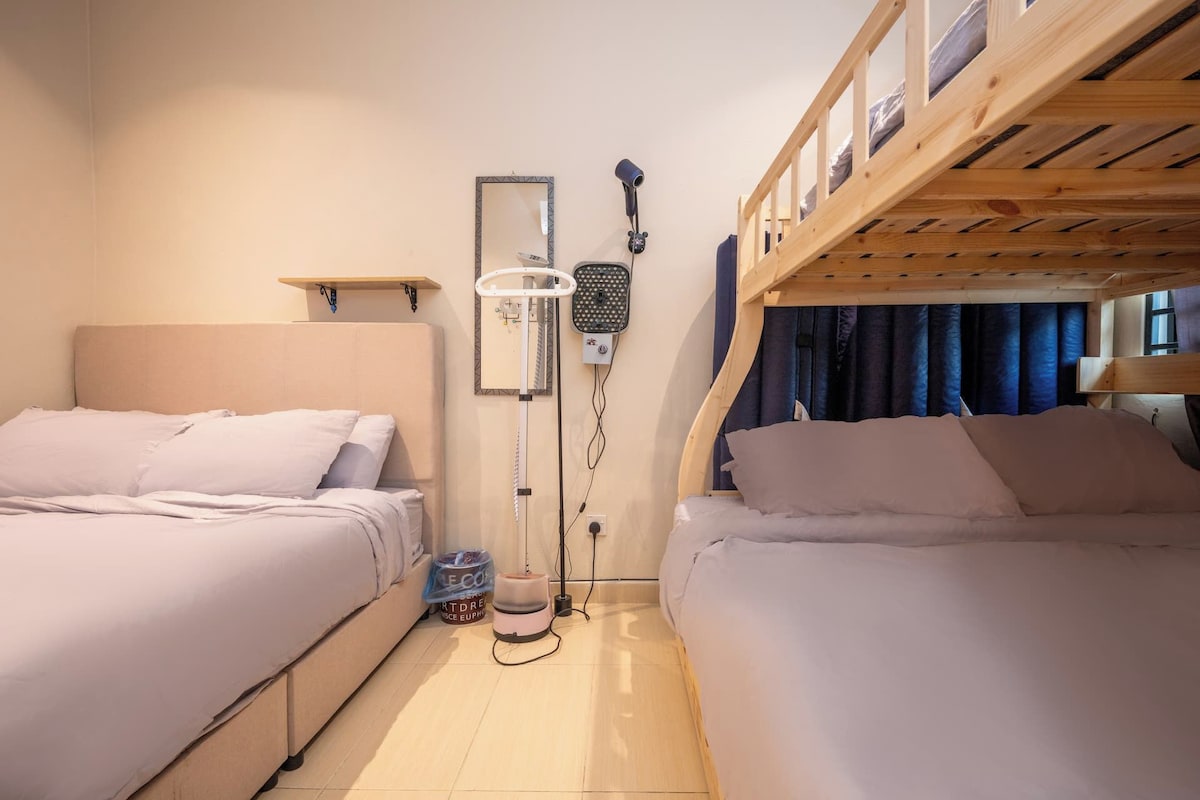 Et lille værelse med to senge, en fastgjort varmeblæser og en ventilator i loftet.