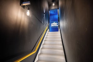 Un escalier avec une rampe jaune menant à une porte bleue ornée d’un logo.