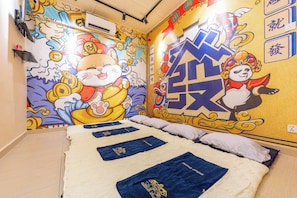 A hotel room with a large bed, a mural on the wall, and a ceiling fan.