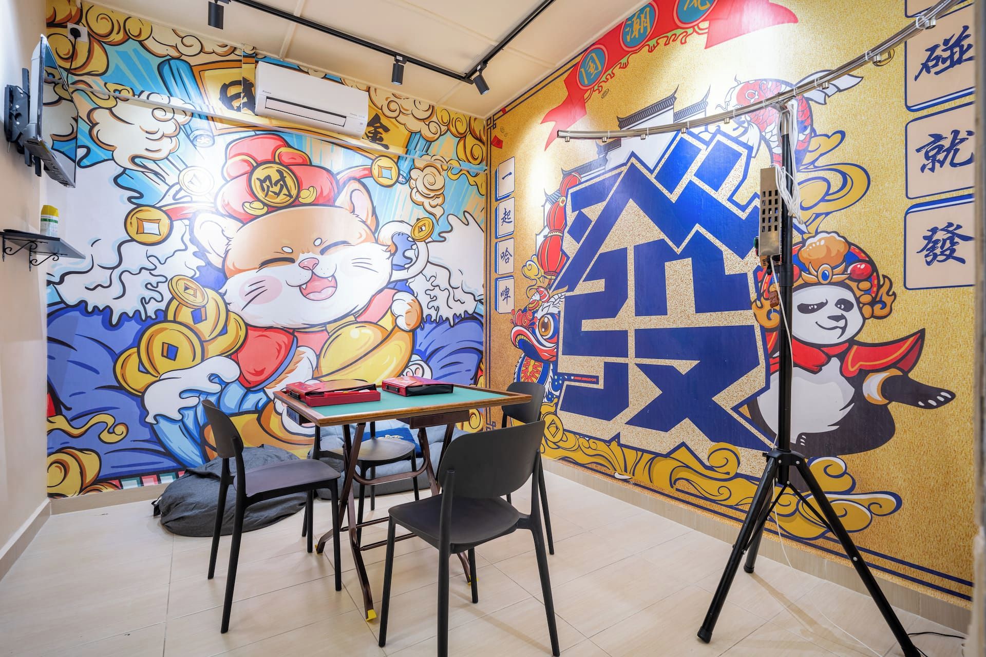 A room with a vibrant mural, a table with chairs, and a tripod.