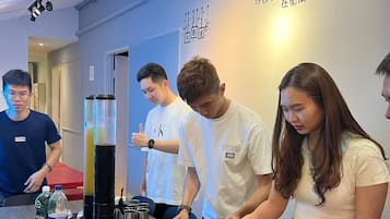 A group of people serving themselves from a buffet with various dishes and beverages.