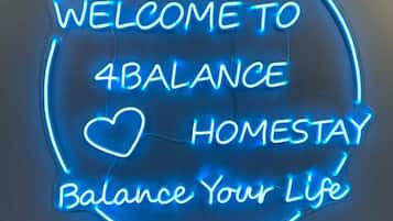A neon sign with the text 'WELCOME TO 4BALANCE HOMESTAY Balance Your Life'.