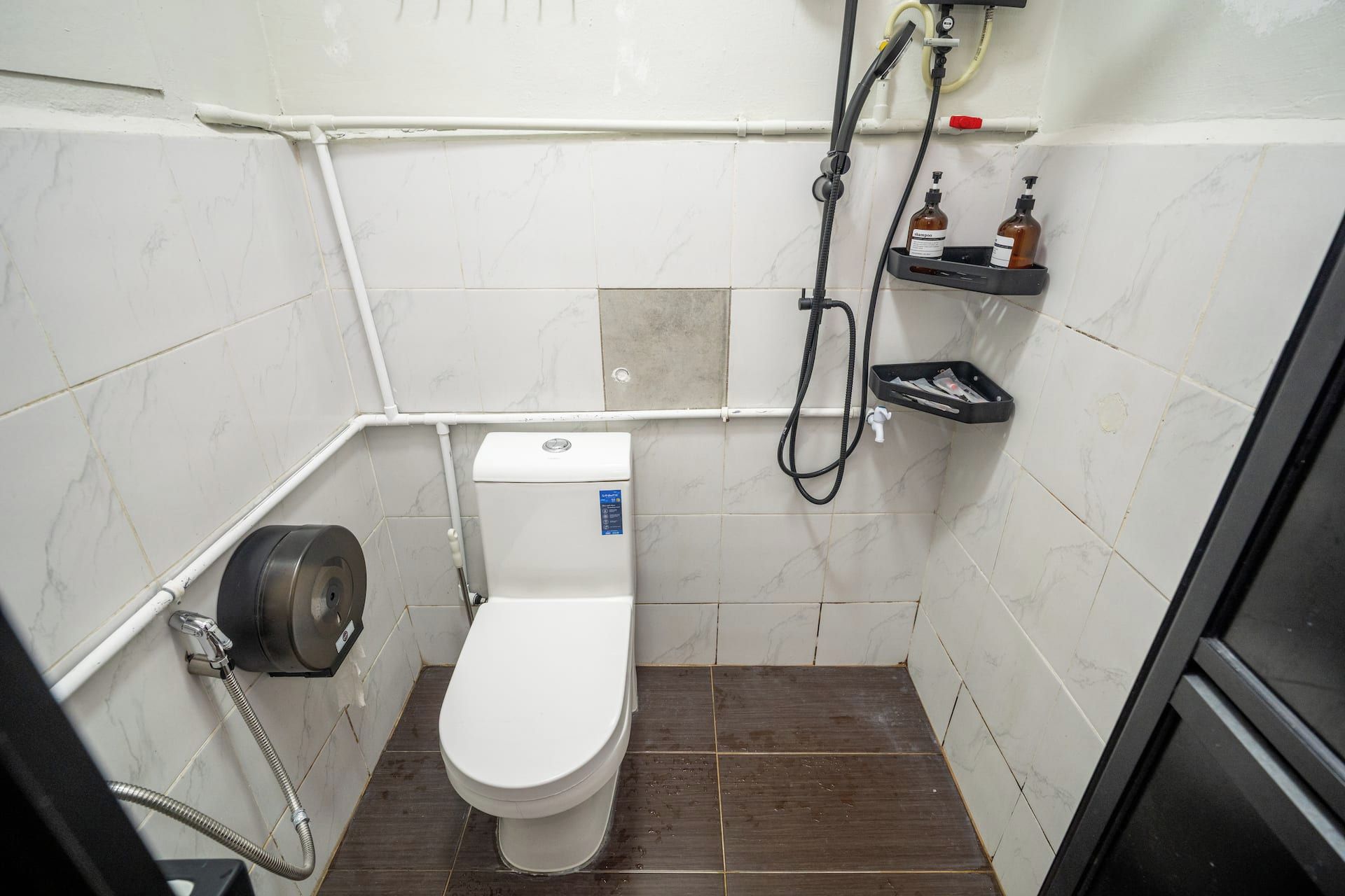 Un baño pequeño y funcional con inodoro, ducha y secamanos.