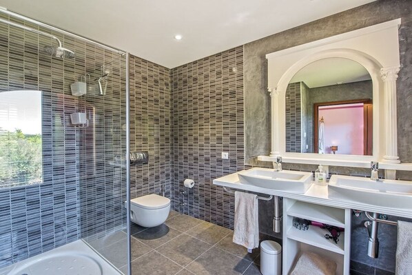 A modern bathroom with a glass shower enclosure, a toilet, and two sinks with a large mirror above. - Finca in Porreres with swimming pool (Porreres)