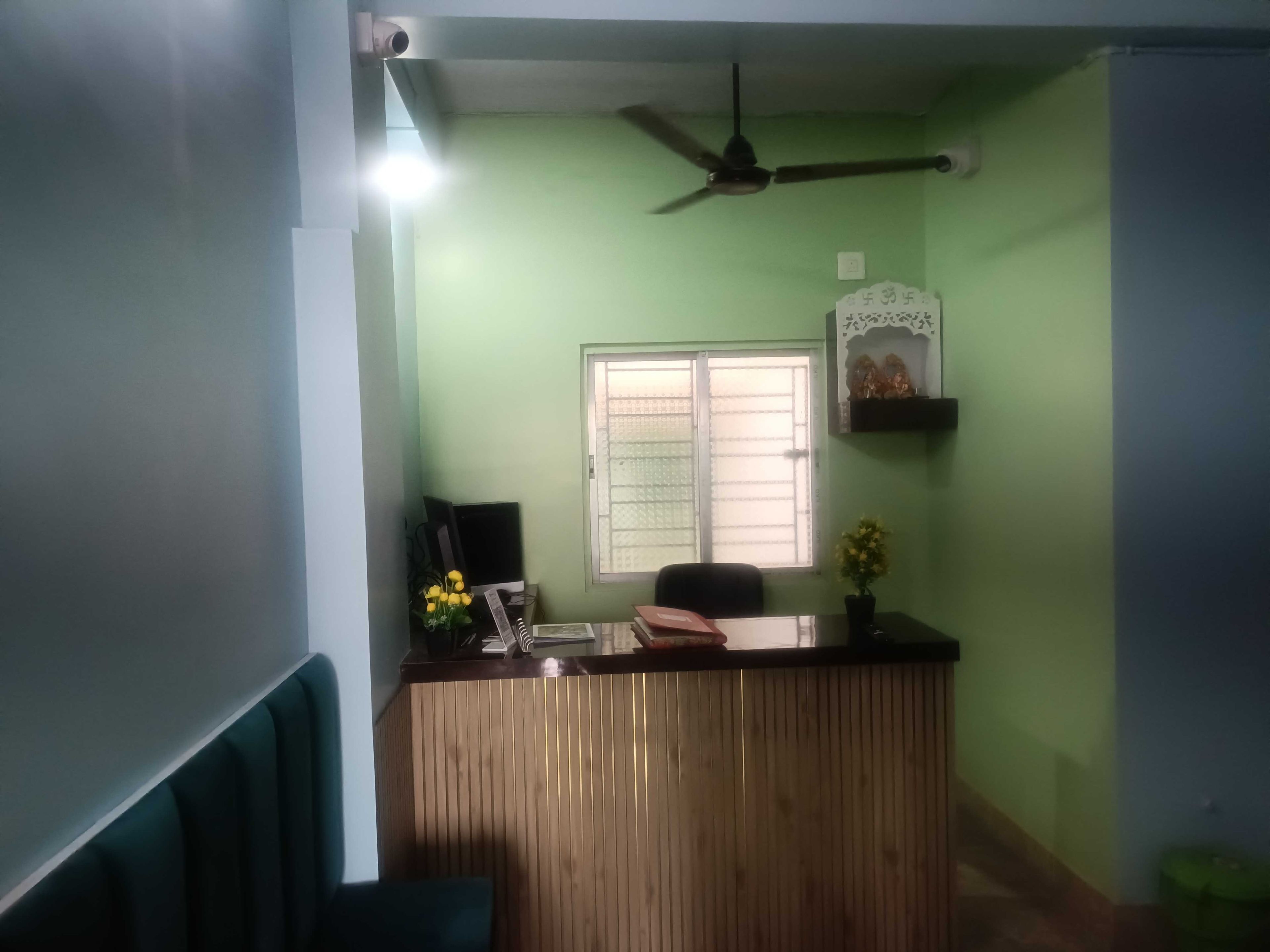 Una recepción con ventilador de techo, una ventana con reja de metal y una estantería de pared con objetos decorativos.