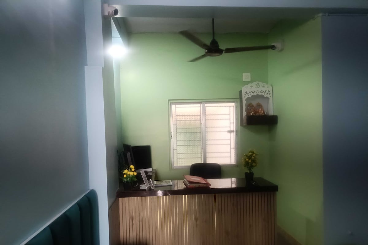 Una recepción con ventilador de techo, una ventana con reja de metal y una estantería de pared con objetos decorativos.