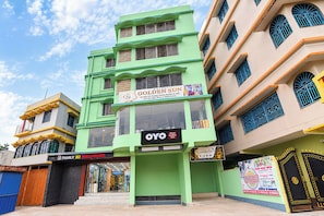 A multi-story building with a prominent green facade, a sign for 'Golden Sun Hotel,' and a storefront for 'Family 3D Wallpaper.' - Hotel O Golden Sun (Barasat)