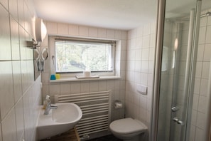 Ein Badezimmer mit Waschbecken, Toilette und einer Duschkabine aus Glas.