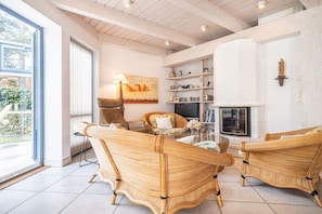 A room with a fireplace, wicker furniture, and a bookshelf. - Up to 6 holidaymakers (Ostseeheilbad Zingst)