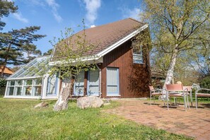 A house with a sloped roof, a glass conservatory, and a brick patio with outdoor seating. - Up to 6 holidaymakers (Ostseeheilbad Zingst)