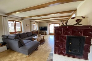 A living room with a sectional sofa, a fireplace, and a television. - Holiday home with 1 bedroom (Reit im Winkl)