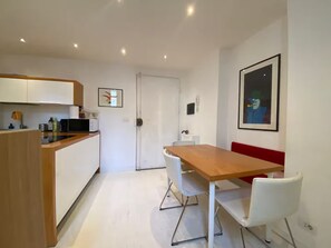A modern kitchen with white cabinets, a wooden dining table, and white chairs. - New Listing (Firenze)