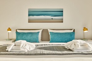A hotel room with a bed, two pillows, a blanket, a painting of a beach scene, and two bedside lamps. - Holiday home with 3 bedrooms (Wenningstedt)