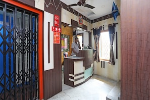 A reception area with a counter, a security sign, and a surveillance sign. - Hotel O South Inn (Kolkata)