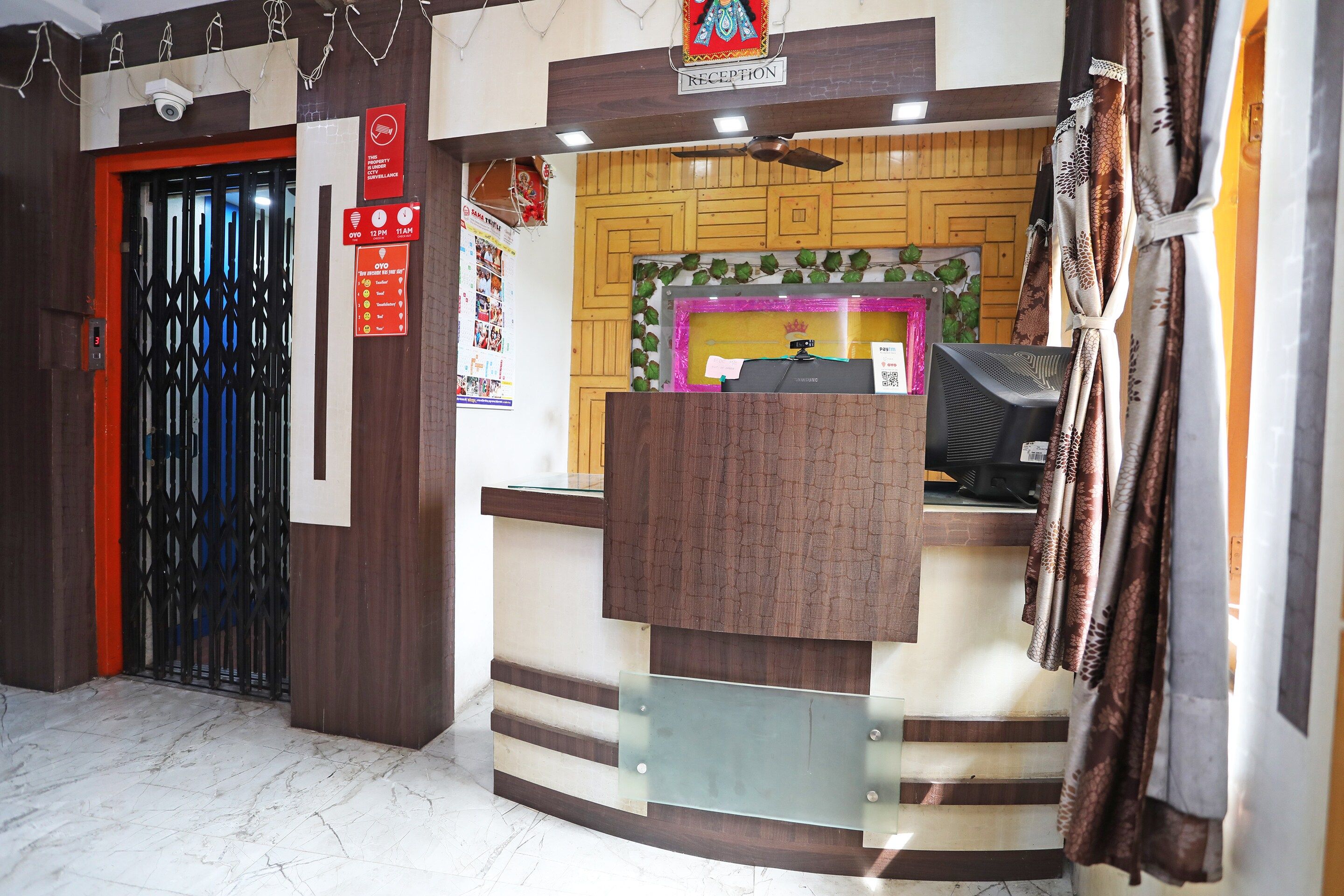 A reception desk with a CCTV camera above, a reception sign, and a door with a security lock.