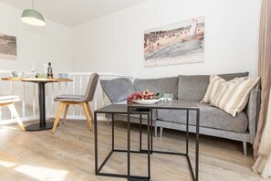A modern living room with a grey sofa, a round wooden table, and a black coffee table. - Wellness Oasis Holiday Home 06 (Wenningstedt)