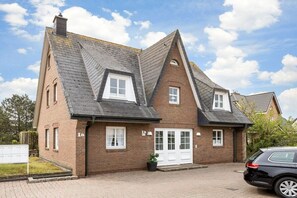 A two-story house with a gabled roof, a front door, and a driveway. - Wellness Oasis Holiday Home 06 (Wenningstedt)