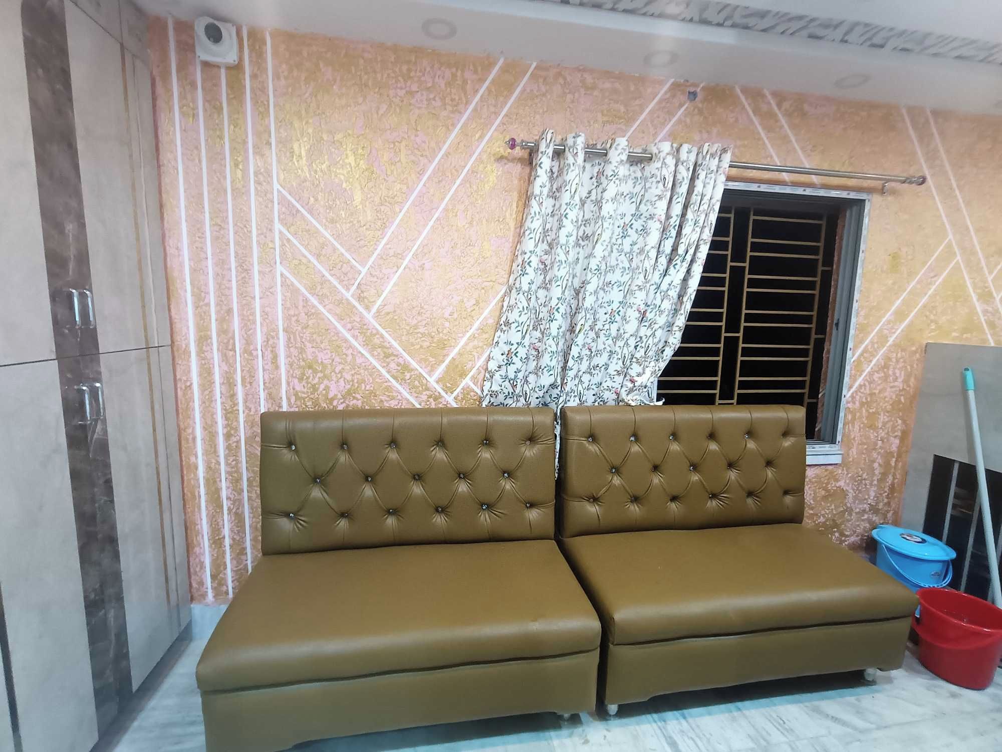 Una habitación con un sofá marrón, una ventana con cortina y un trapeador en el suelo.